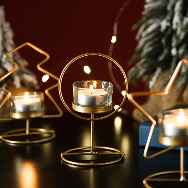 Decorative candle holders with lit candles on a dark surface, surrounded by Christmas trees.