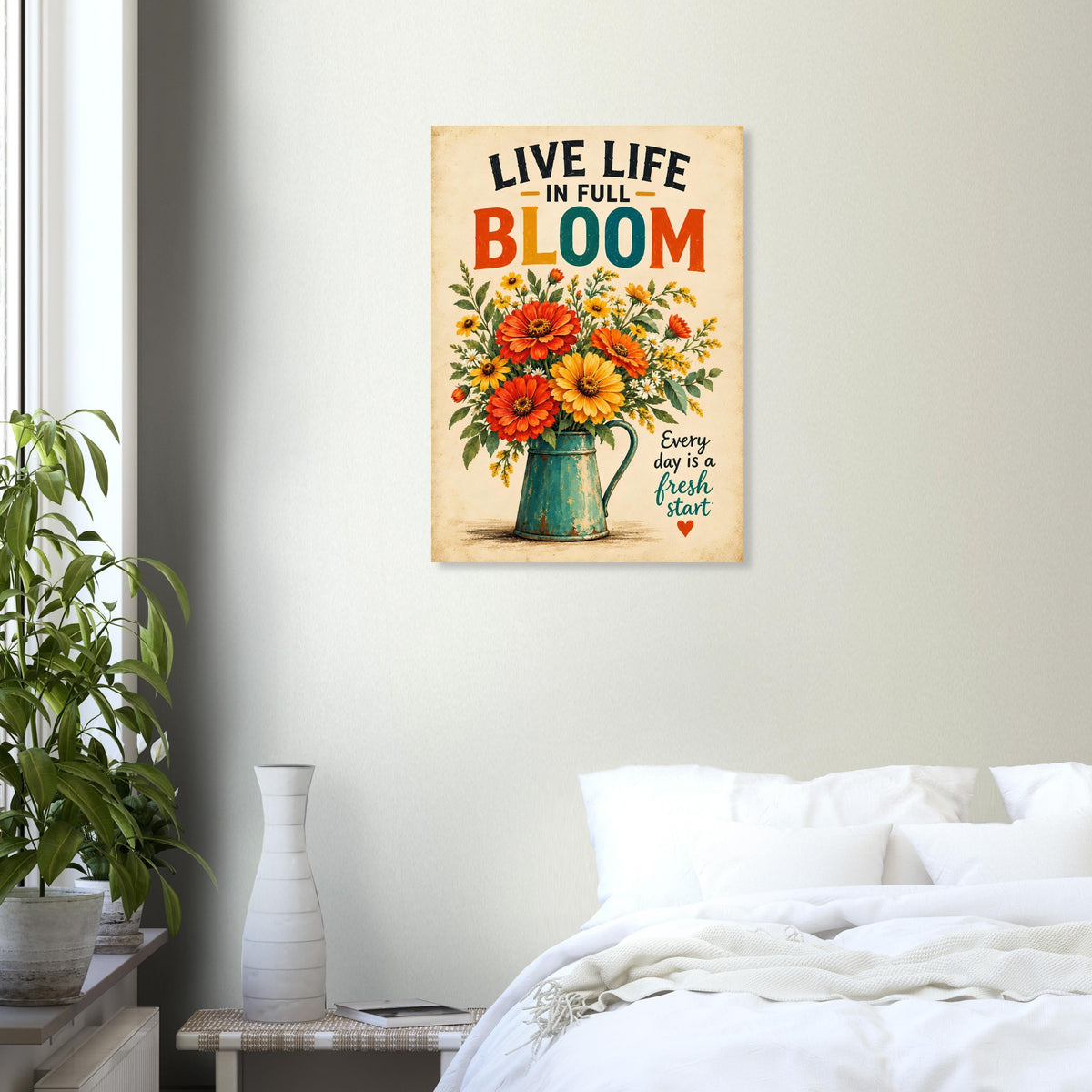 A vertical metal wall art print featuring a colorful bouquet of sunflowers and roses in a green pitcher, with the text 'LIVE LIFE IN FULL BLOOM' and 'Every day is a fresh start', displayed on a light gray wall above a bed in a styled bedroom.
