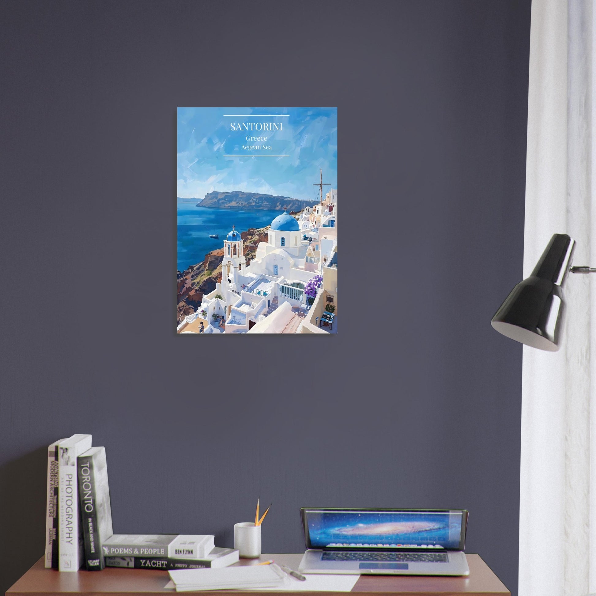 Poster of Santorini on a wall above a desk with books and a laptop.