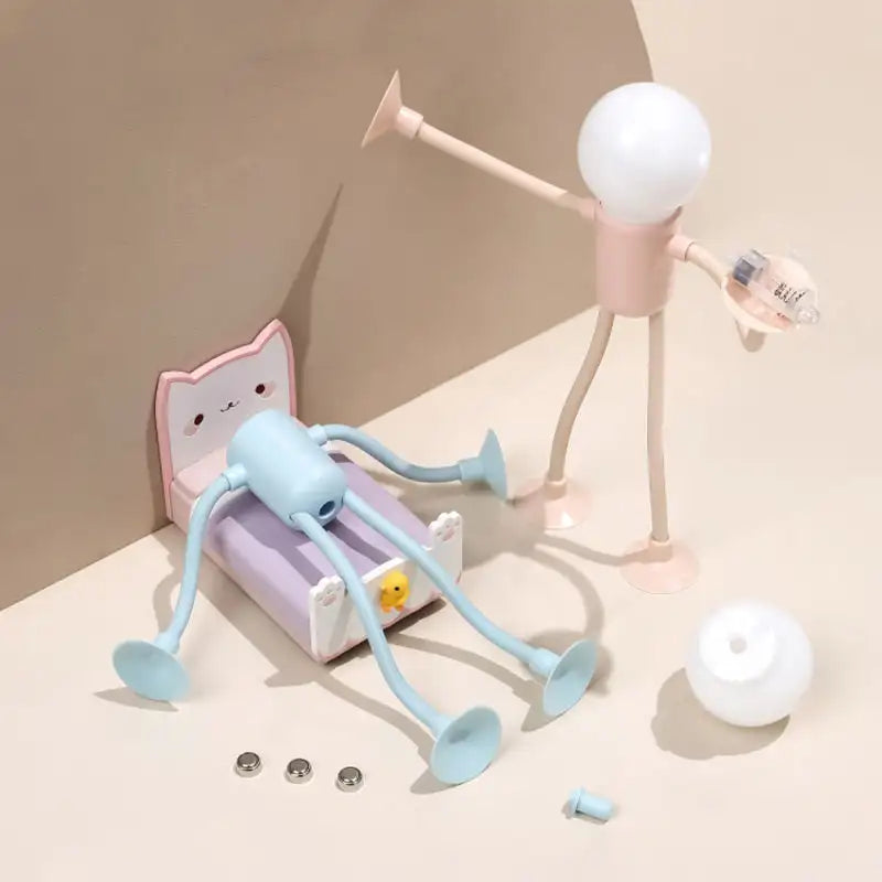 Creative desk setup with a light blue octopus-shaped lamp, pink lamp, and white bulb on a beige surface.