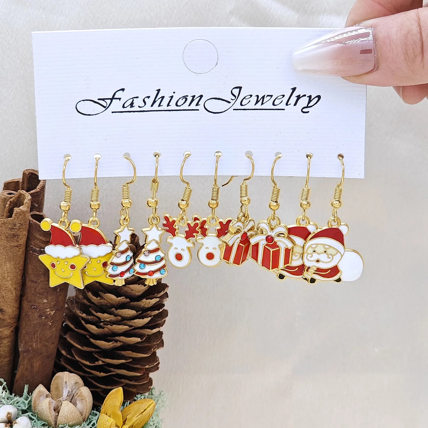 Set of Christmas-themed earrings on a 'Fashion Jewelry' card with decorative items in the background.