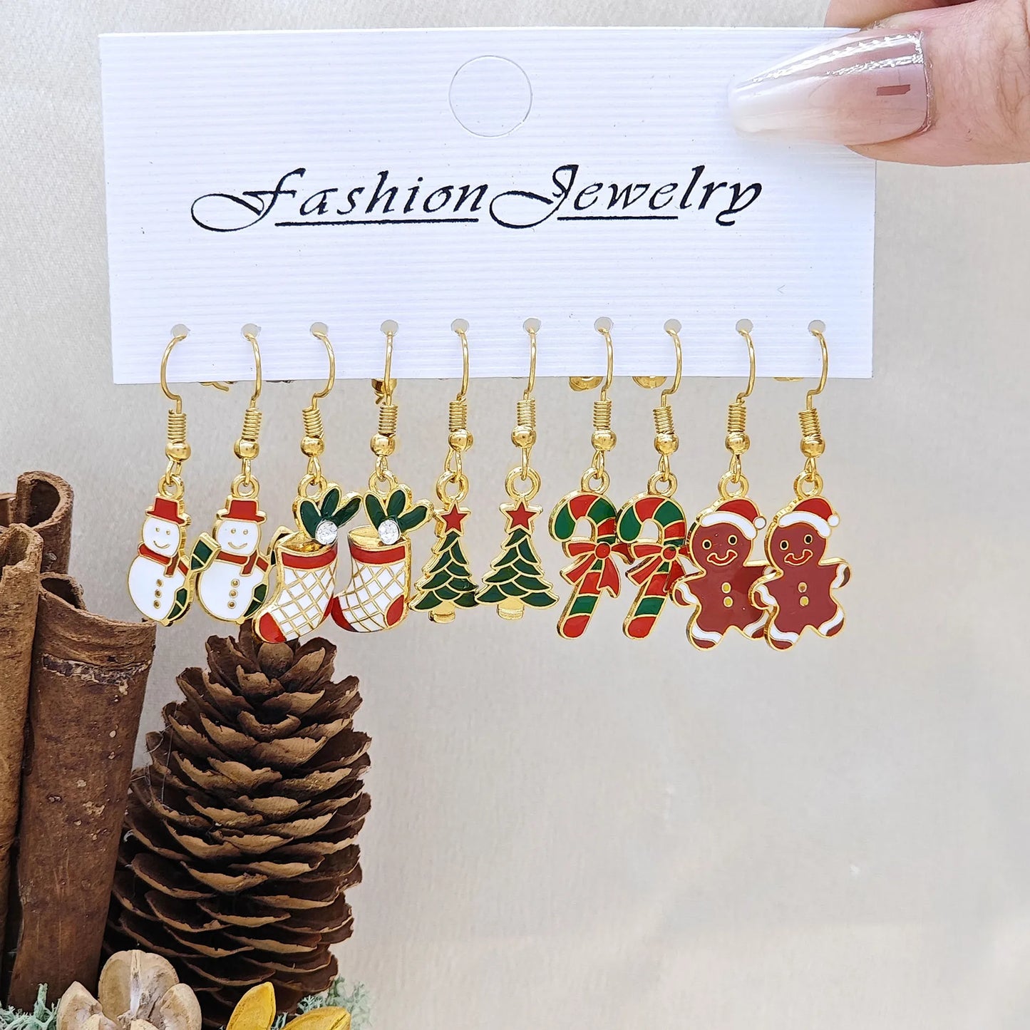 Set of Christmas-themed earrings on a 'Fashion Jewelry' card with decorative items in the background.
