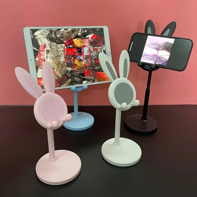 Three phone stands with bunny ears on a black surface against a pink background