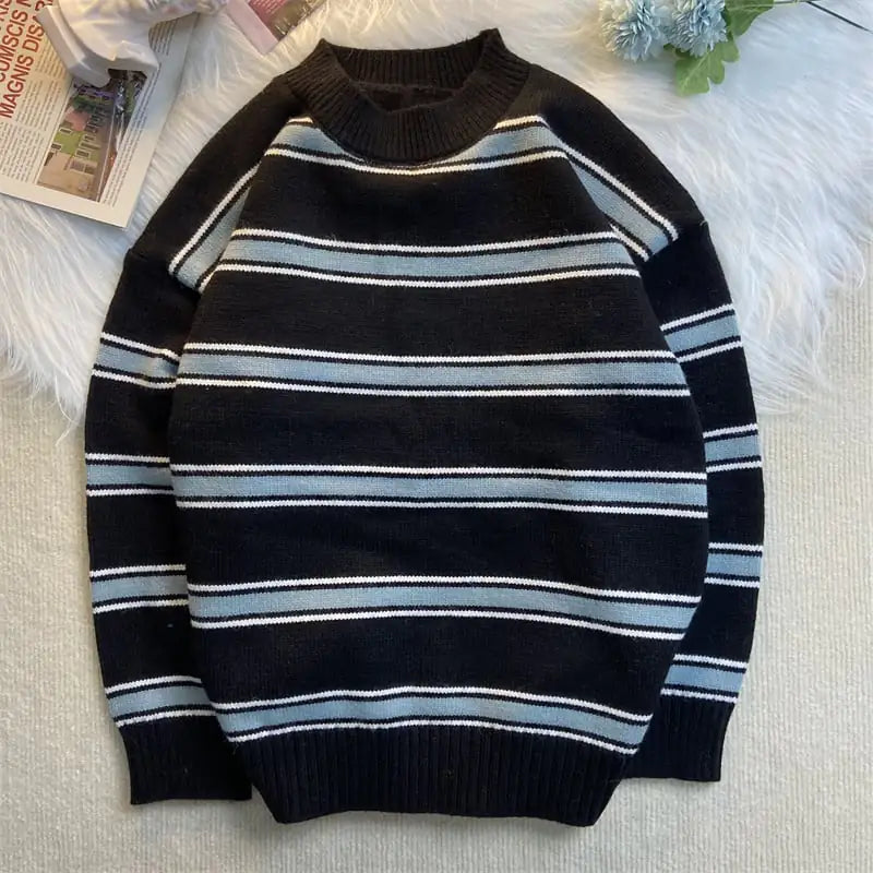 Black and blue striped sweater on a light gray surface with a magazine and decorative items in the background.