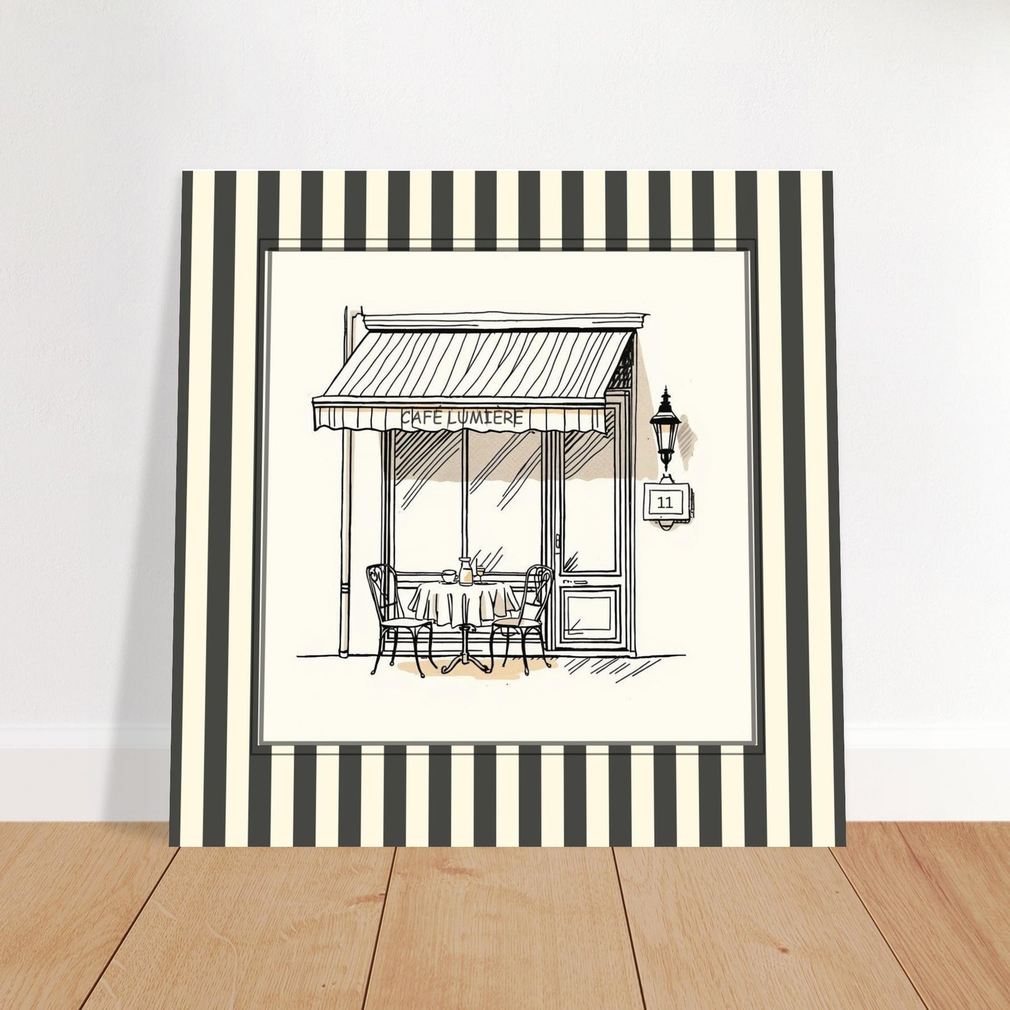 Square French café wall art print leaning against wall in Scandinavian workspace