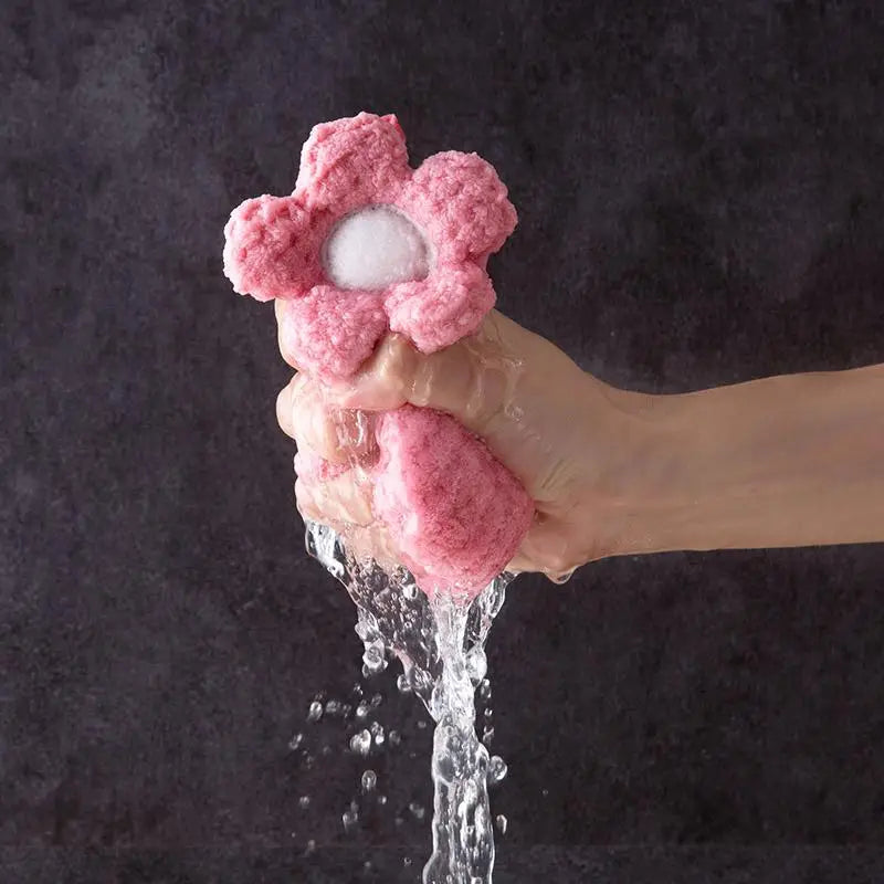Hand holding a pink flower-shaped water faucet against a dark background