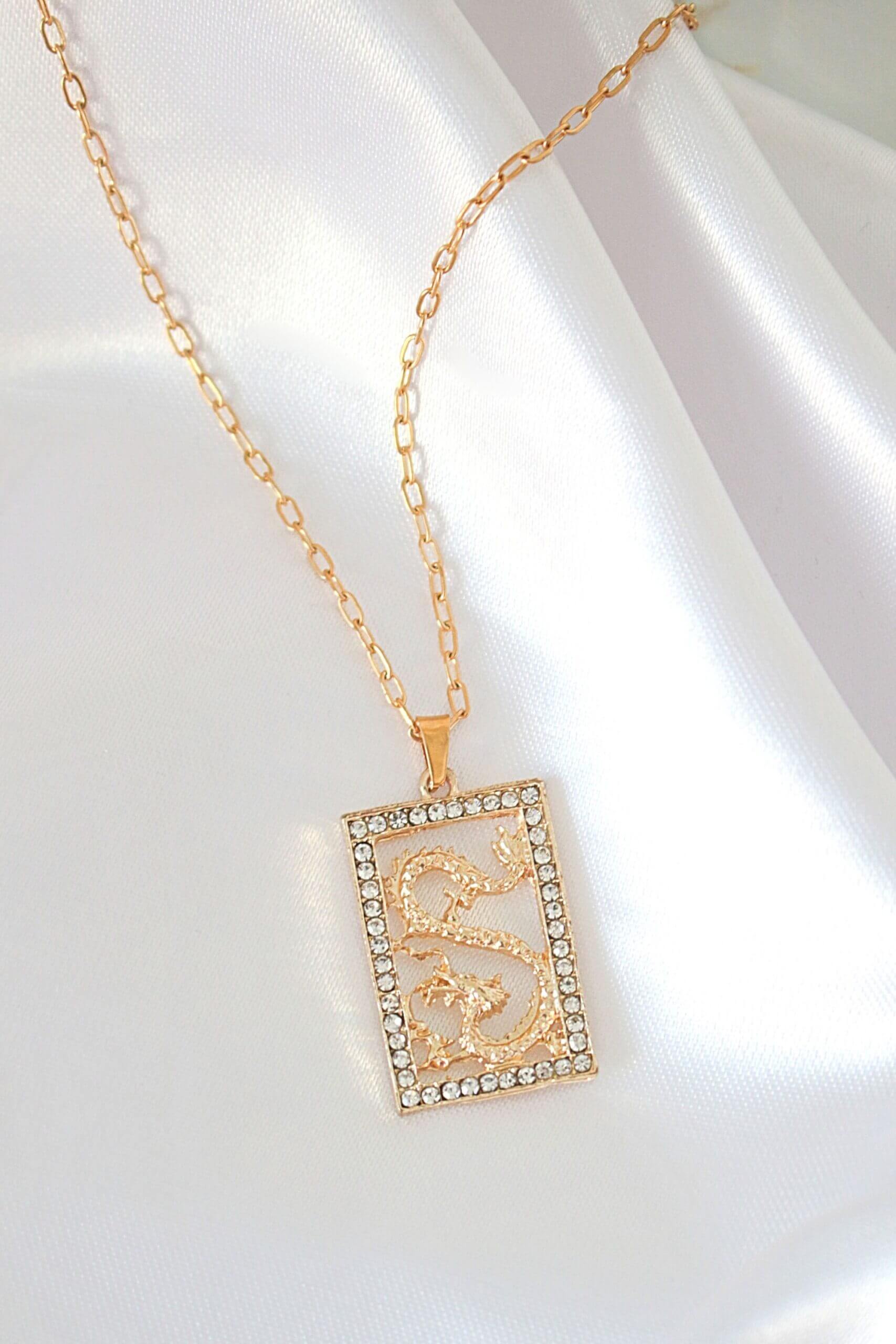 Gold necklace with a rectangular pendant on a white background