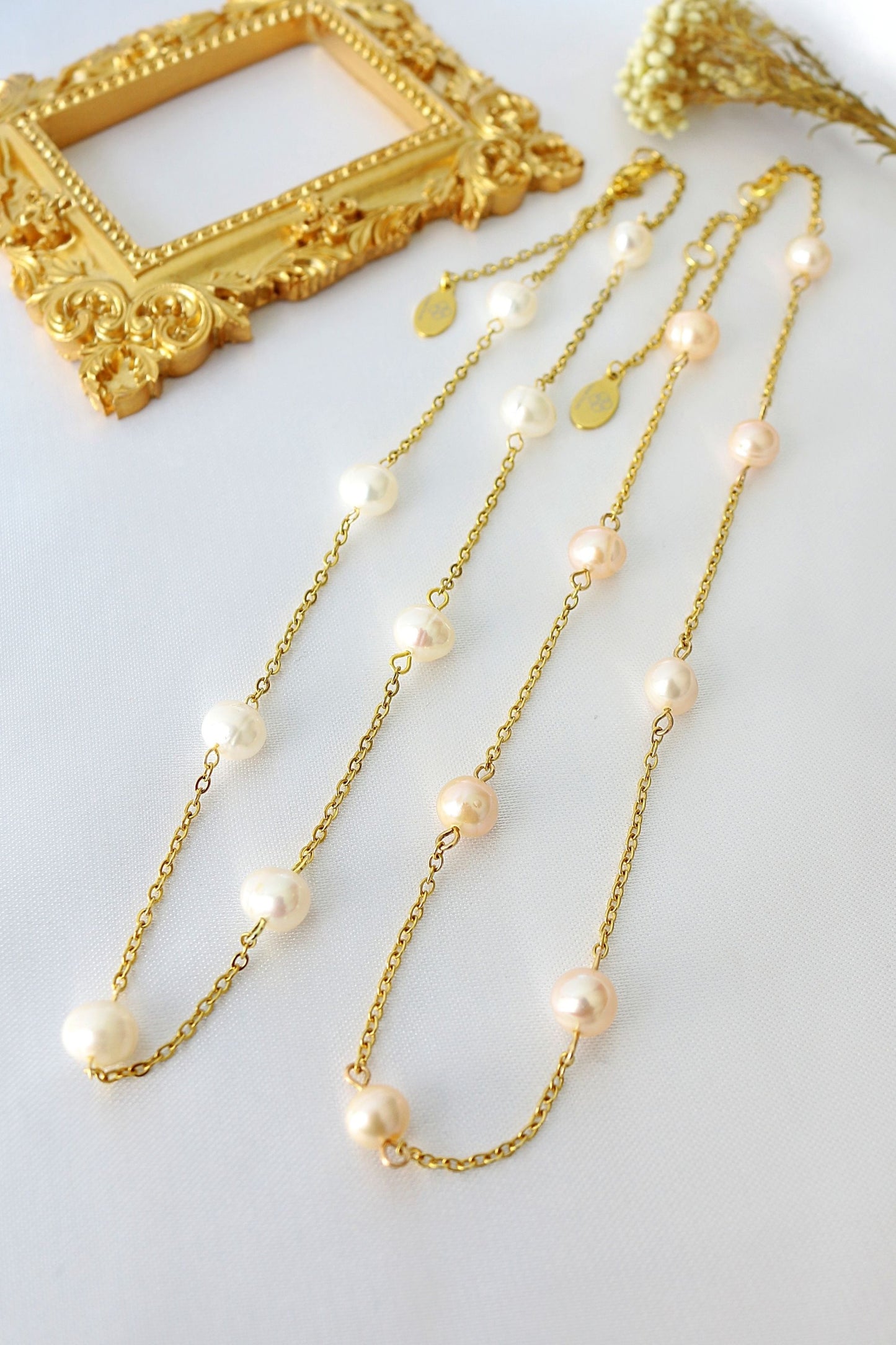 Gold chain necklace with pearls on a white background