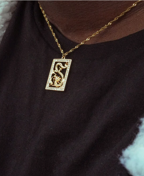 Gold necklace with a rectangular pendant on a dark background