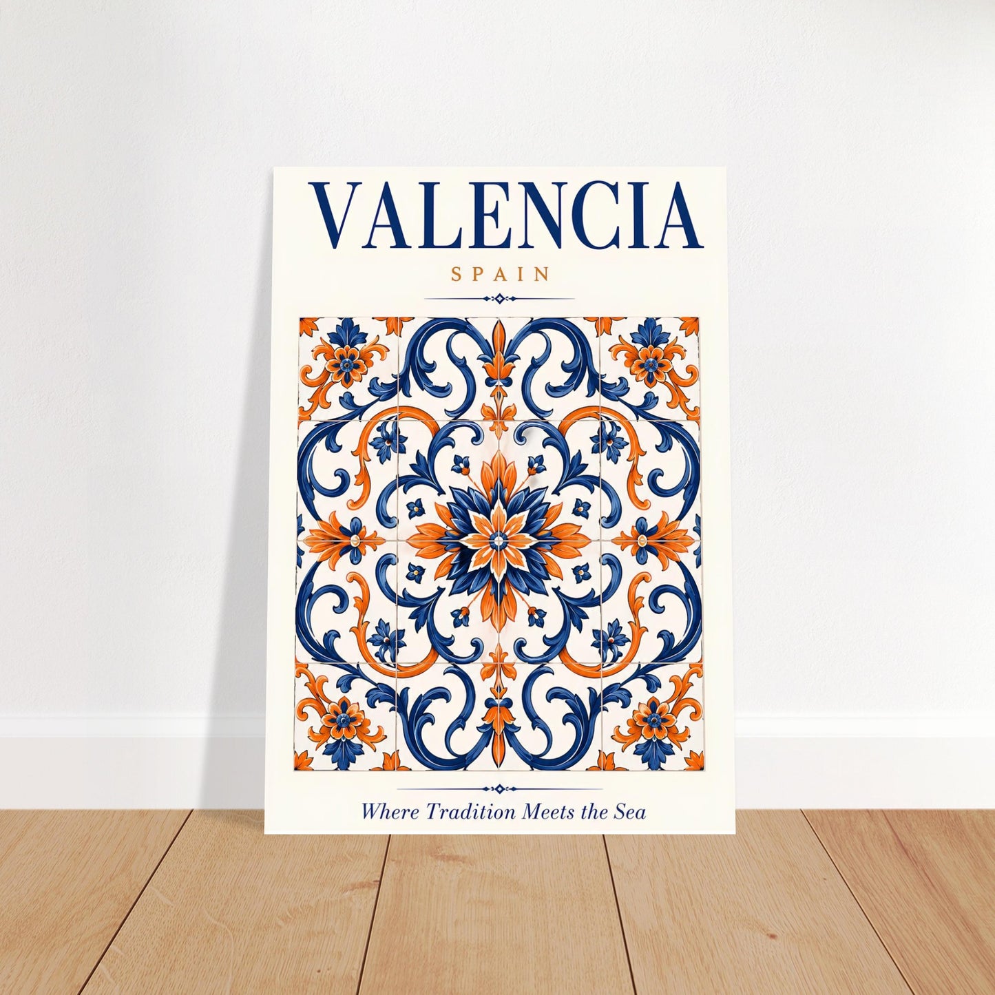 A vertical art print featuring a decorative Valencia, Spain tile pattern in navy blue, orange, and white, leaning against a white wall on a light wood floor.