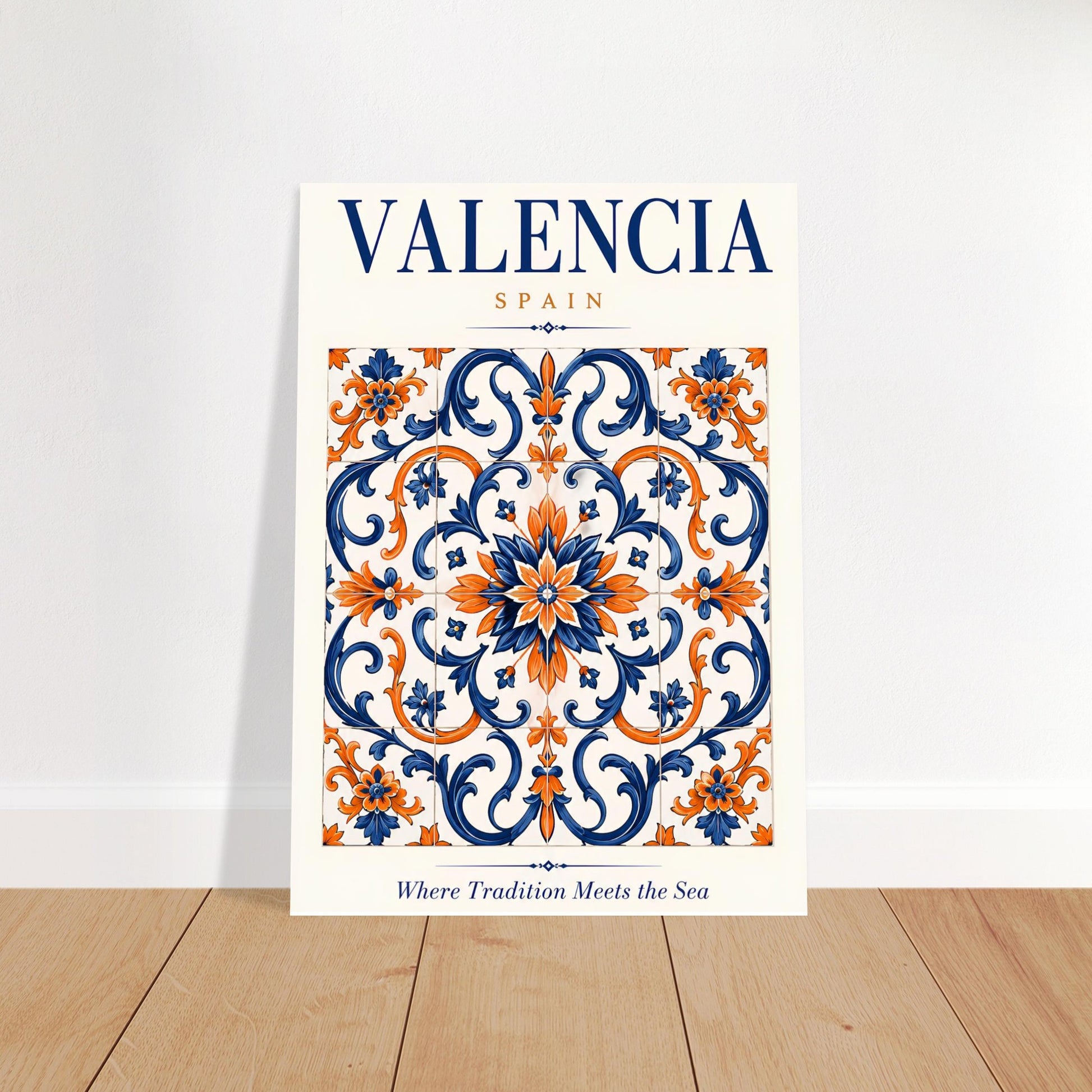 A vertical art print featuring a decorative Valencia, Spain tile pattern in navy blue, orange, and white, leaning against a white wall on a light wood floor.