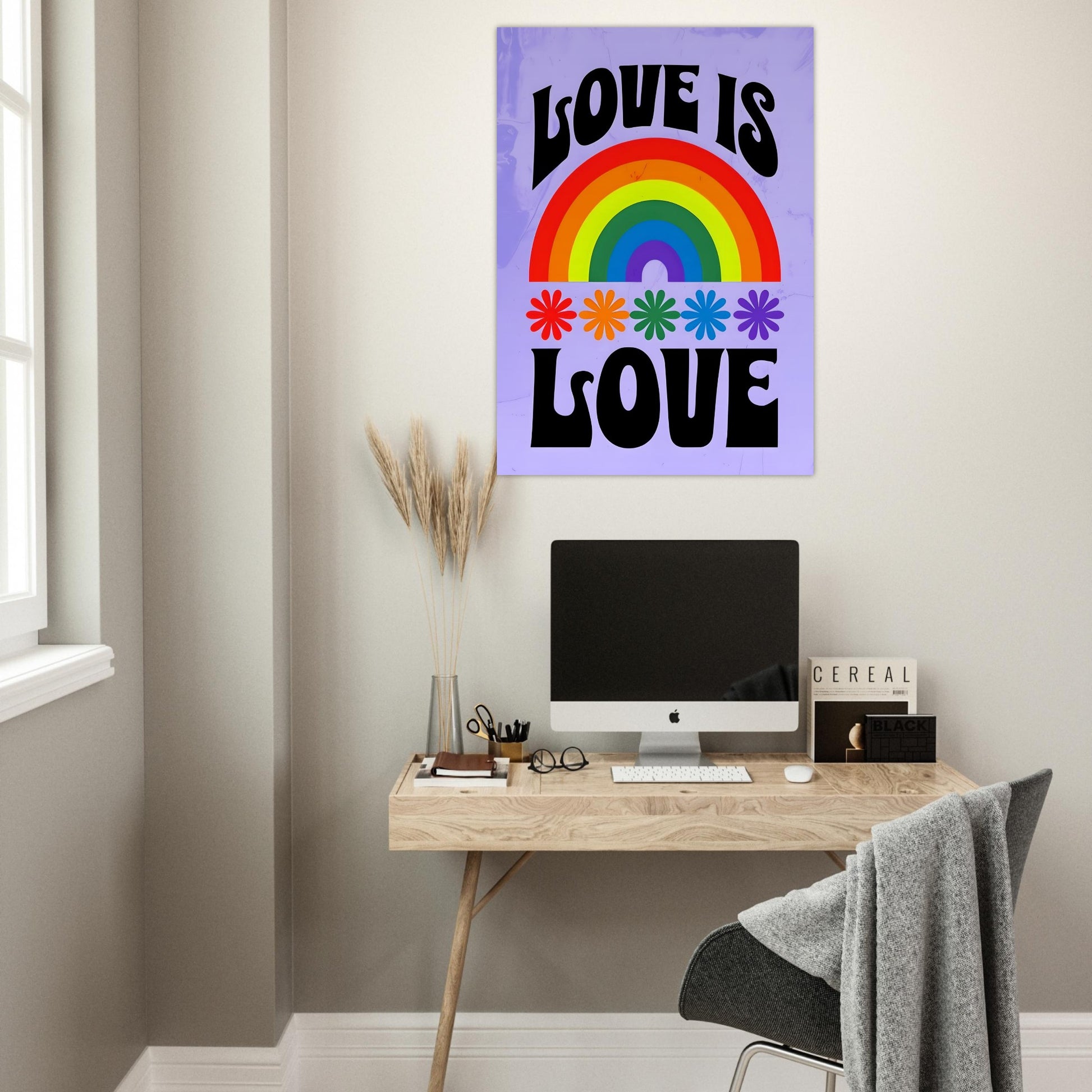 Desk with computer monitor, decor items, and a 'Love is Love' rainbow poster on a wall.