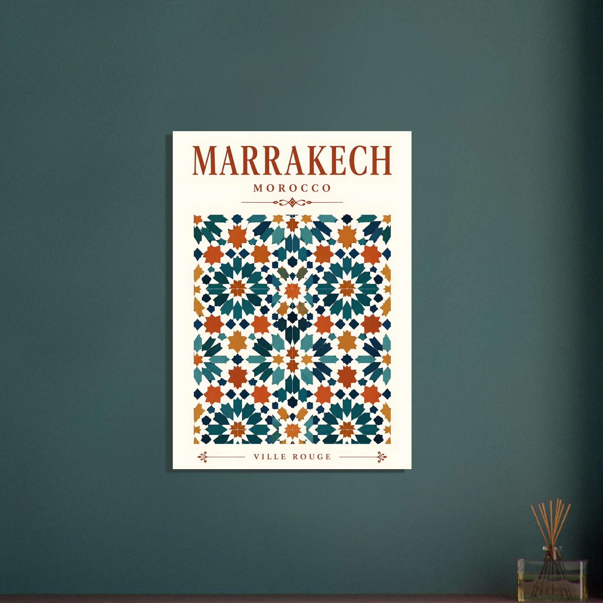 A vertical travel poster of Marrakech, Morocco, featuring a cream background with a colorful geometric tile pattern in teal, orange, and white. The words 'MARRAKECH MOROCCO' are printed in a reddish-brown serif font at the top, and 'VILLE ROUGE' at the bottom.