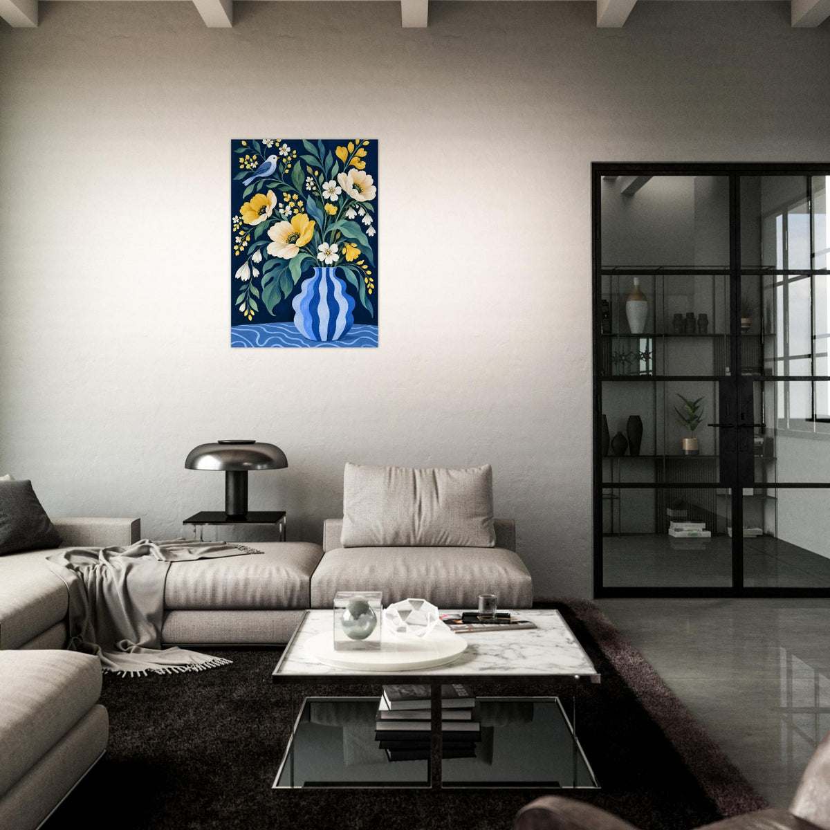 A framed vertical canvas print of a floral and bird painting in blue, yellow, and white hangs on a light gray wall in a modern living room setting with a sofa, coffee table, and black shelving unit.