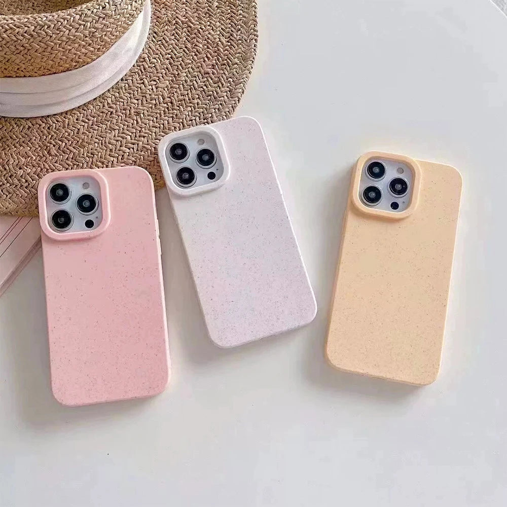 Three phone cases in pink, white, and beige on a light surface with a straw hat in the background.