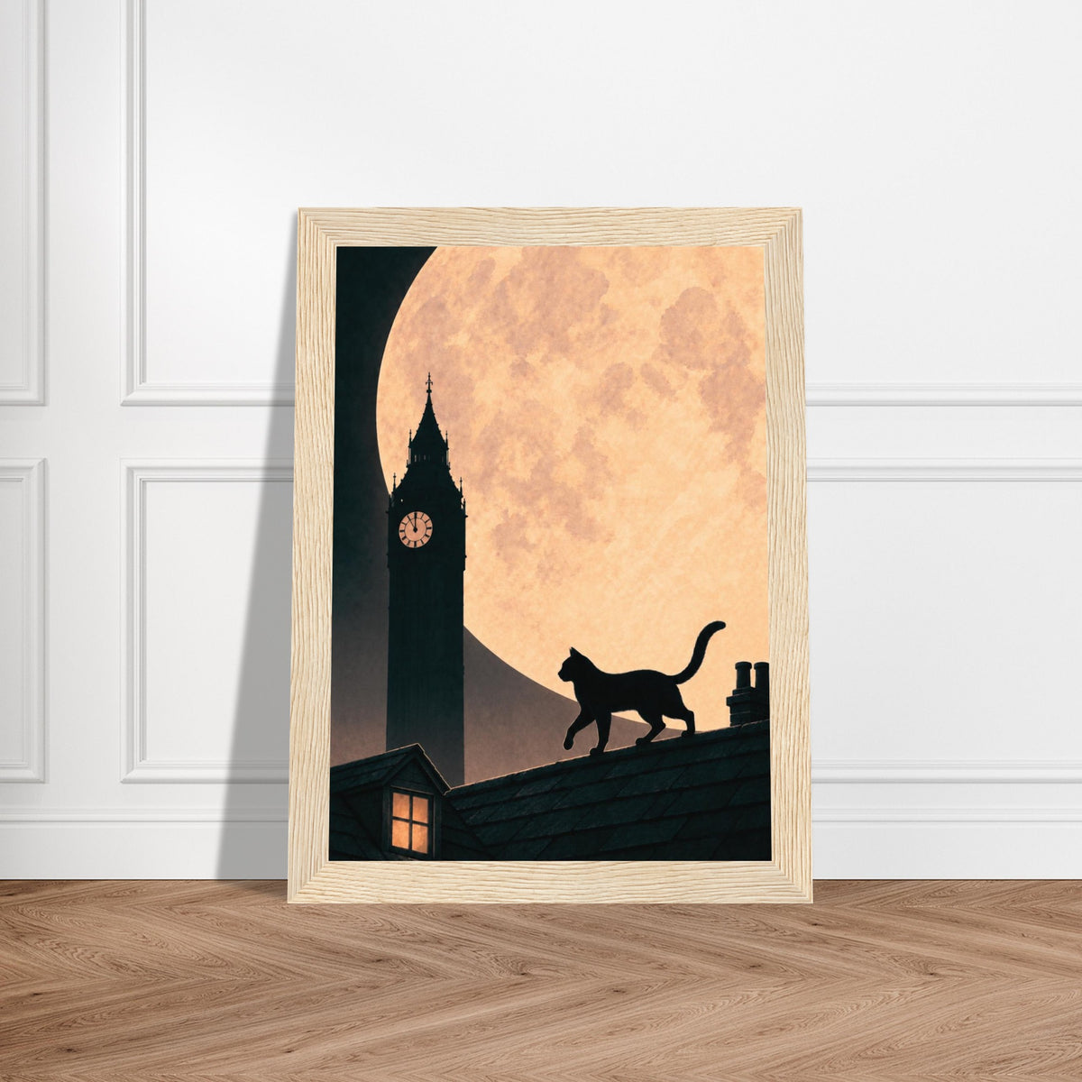 A framed art print leaning against a white paneled wall on a light wood floor. The print shows a black silhouette of a cat walking on a roof against a large warm peach moon and a dark clock tower.
