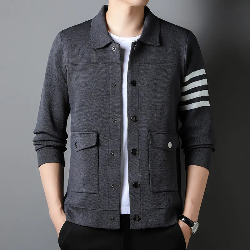Dark gray jacket with white stripes on sleeves worn by a person against a gray background