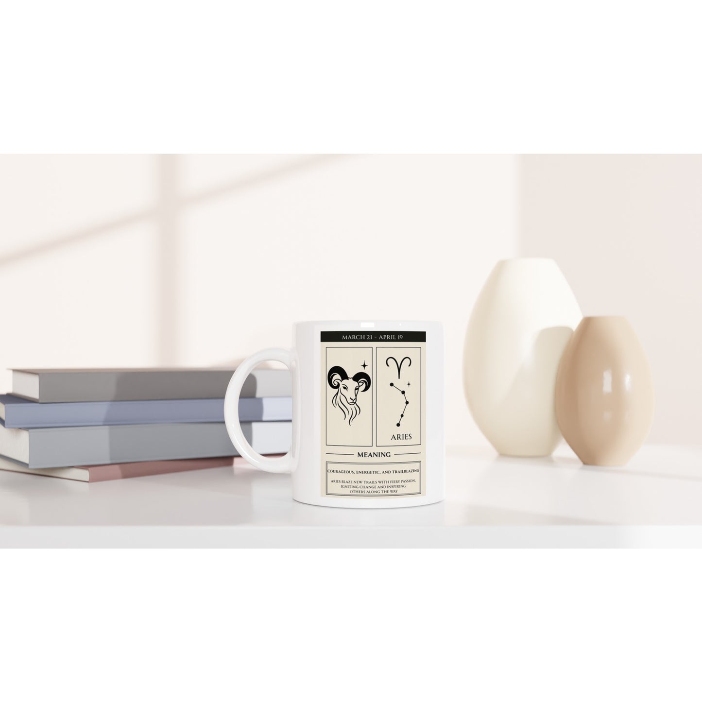 Mockup of a white ceramic mug featuring the Aries zodiac poster design (ram illustration, glyph, constellation, dates, and meaning) on a white tabletop, with stacked books and beige vases softly blurred in the background.
