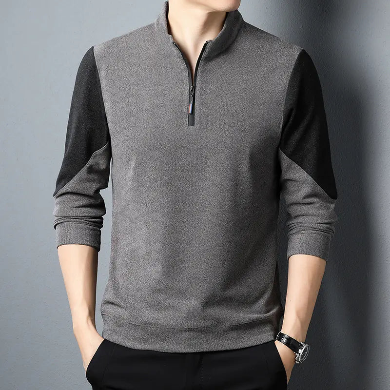 Person wearing a gray and black long-sleeve shirt with a zipper on a gray background