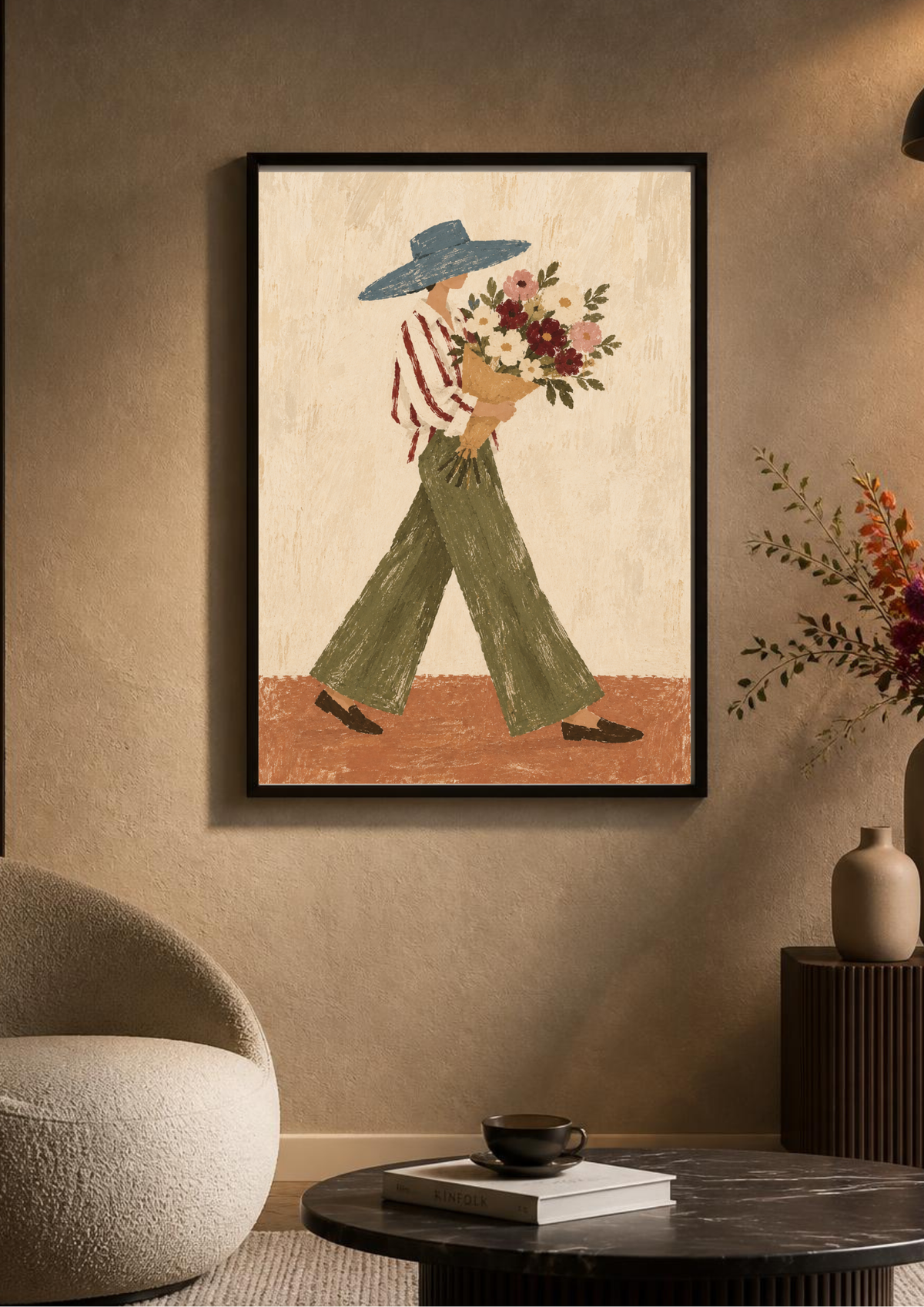 A framed art print featuring a stylized figure in a wide-brimmed blue hat, red-and-white striped shirt, and green pants carrying a bouquet of flowers, displayed on a warm beige wall in a modern living room setting.
