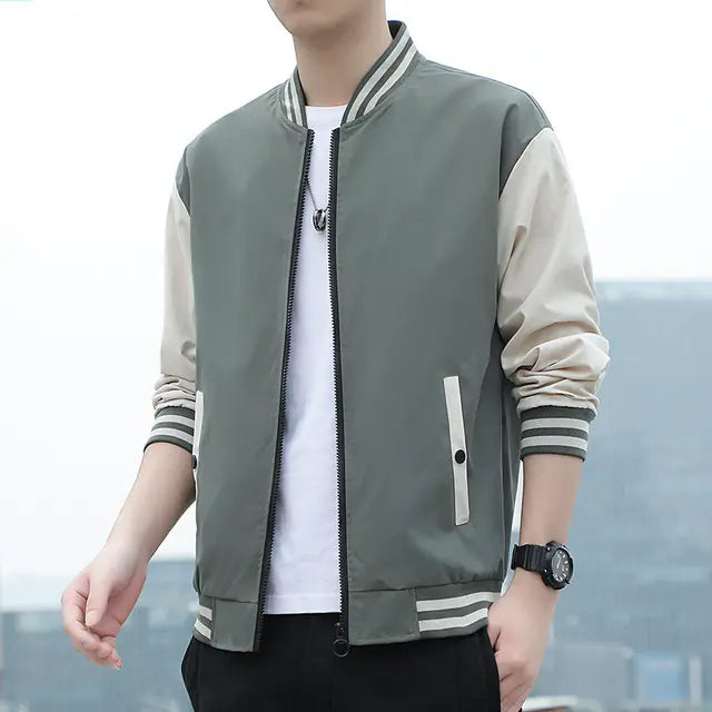 Person wearing a gray and beige bomber jacket with a blurred background