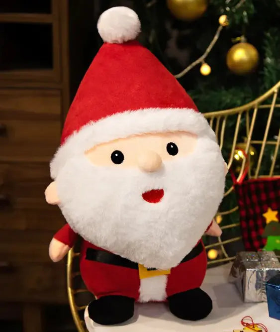 Plush Santa Claus toy in front of a decorated Christmas tree with gold ornaments.
