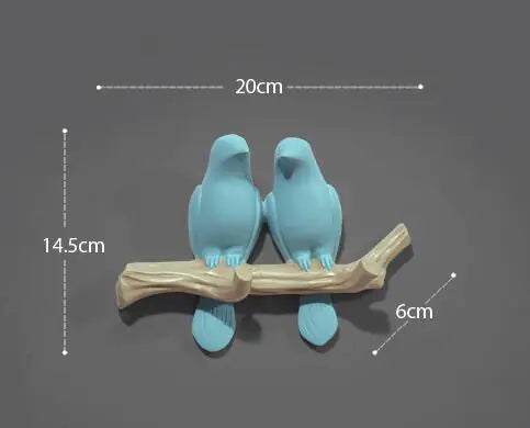 Two blue bird figurines on a branch with measurements on a dark background