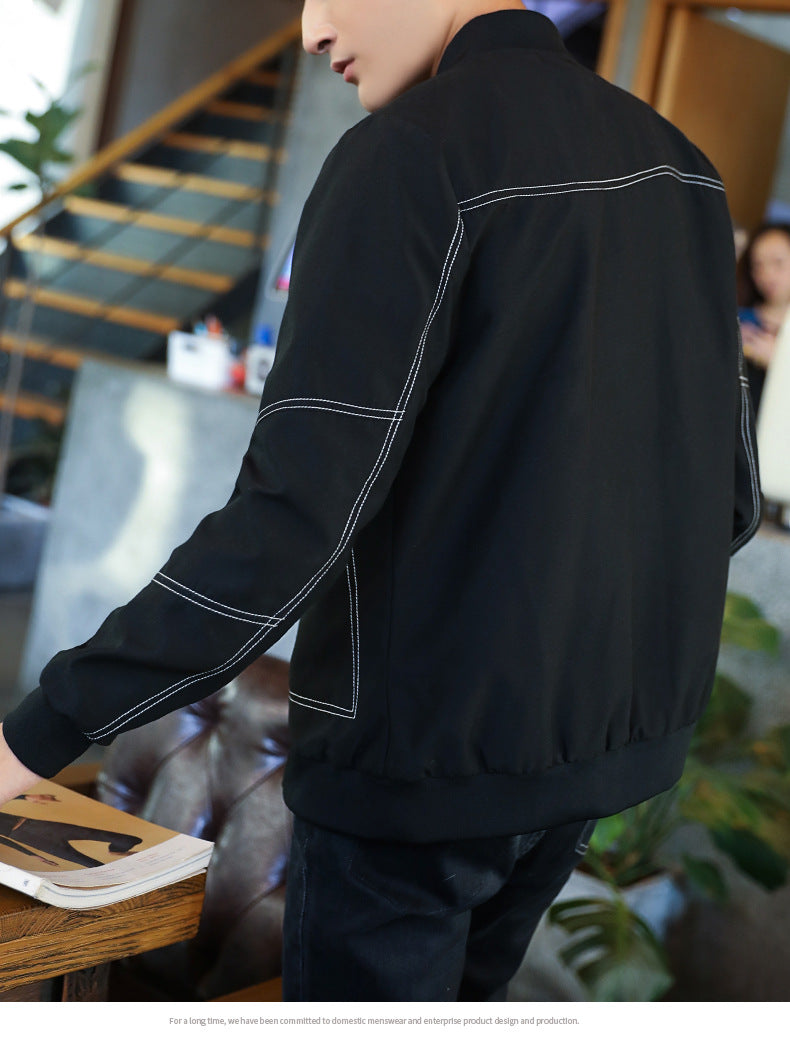 Person wearing a black jacket with white stitching in an indoor setting