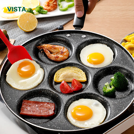 Vista brand frying pan with fried eggs, vegetables, and meat on a wooden table.