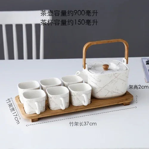 Marble-patterned teapot set with six cups on a wooden tray against a white background.