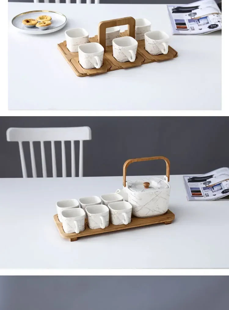 Ceramic teapot with wooden handle and matching cups on a wooden tray, set against a white background.