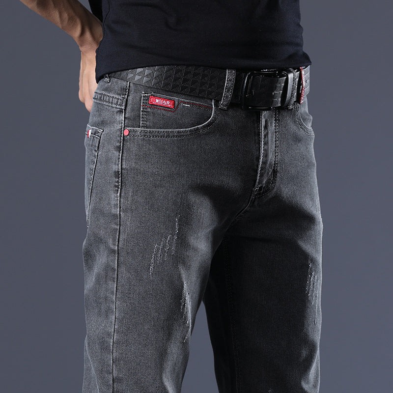 Person wearing dark gray jeans with a belt on a dark background
