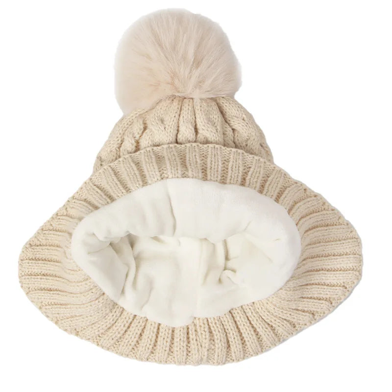 Knitted beige beanie with a white pom-pom on a white background