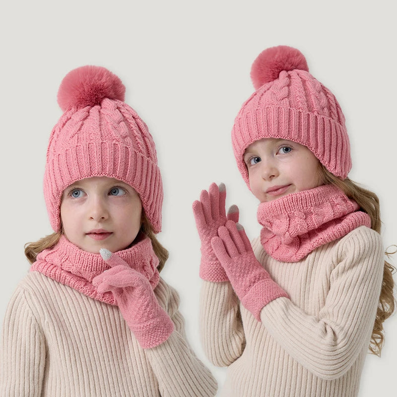 Two children wearing pink knit hats, scarves, and gloves on a light background