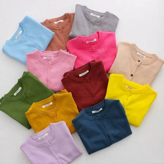 Assorted colorful children's cardigans arranged in a grid on a light background