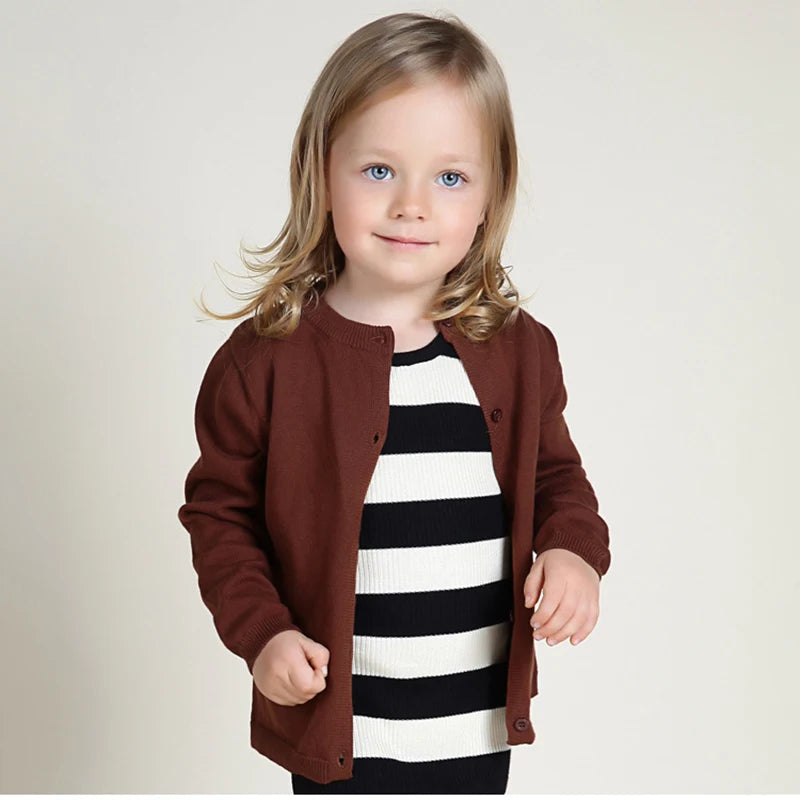 Child wearing a brown coat over a striped shirt on a plain background
