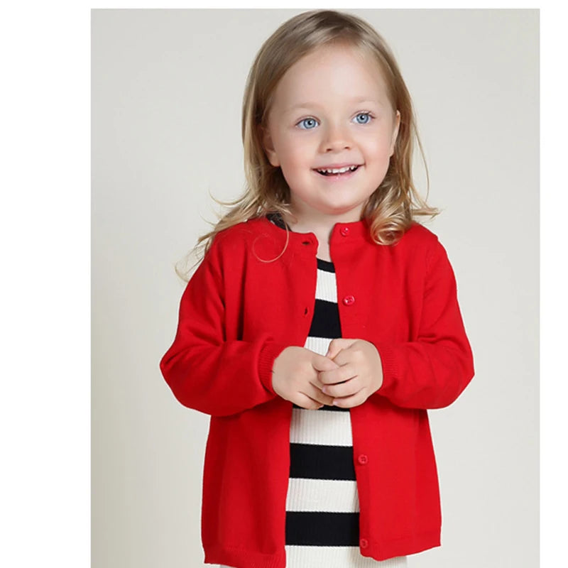 Child wearing a red cardigan over a black and white striped dress on a plain background