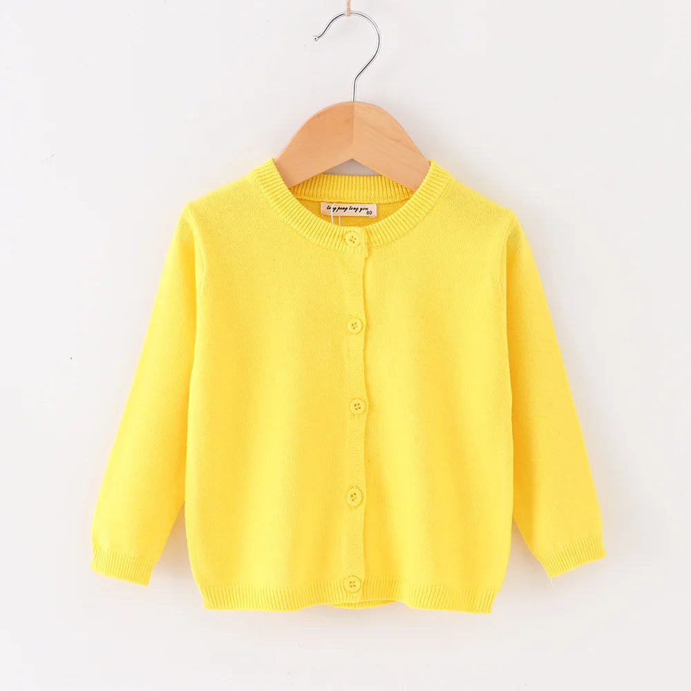 Yellow cardigan on a wooden hanger against a white background