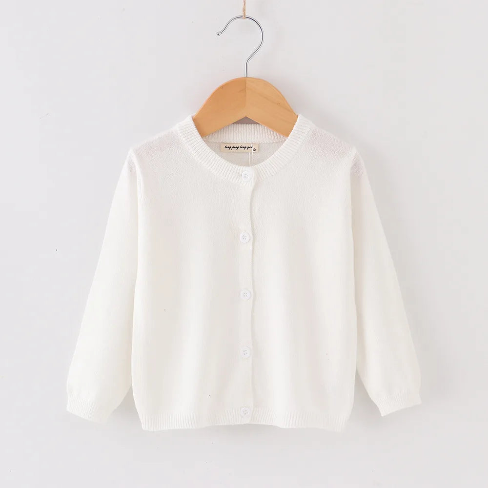 White baby cardigan on a wooden hanger against a white background