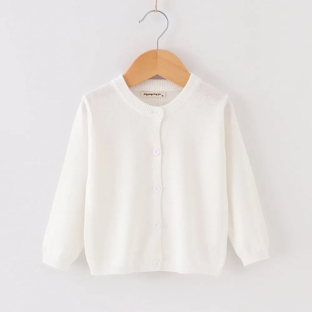 White cardigan on a wooden hanger against a white background