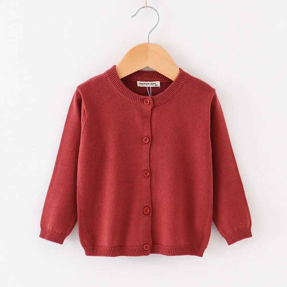 Red children's cardigan on a wooden hanger against a white background