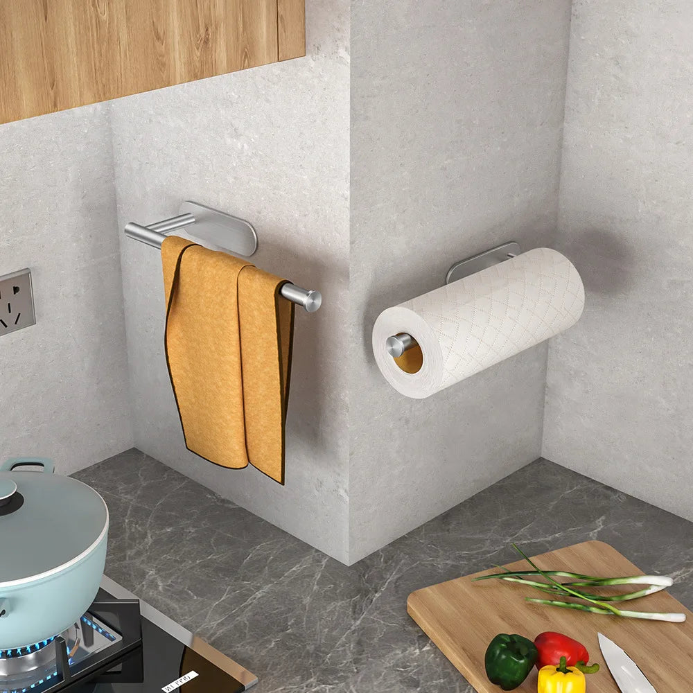Kitchen corner with a yellow towel on a rack, paper towel holder, and cutting board with vegetables.