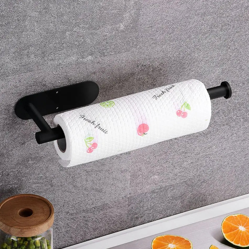 Roll of paper towel with decorative design on a black holder against a gray wall.