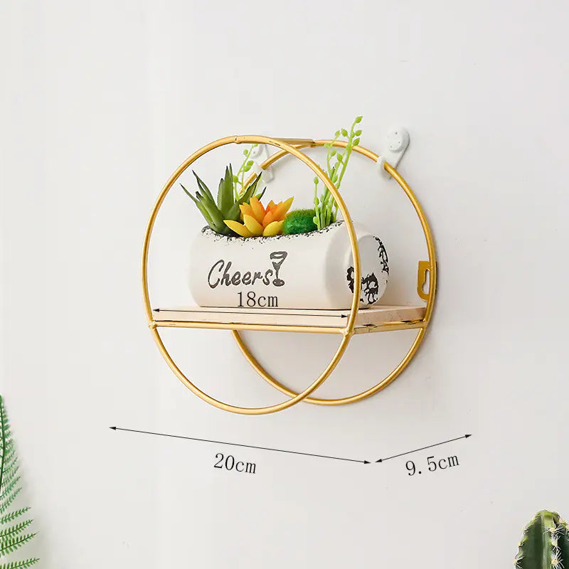 Wall-mounted gold metal shelf with decorative plants on a white background
