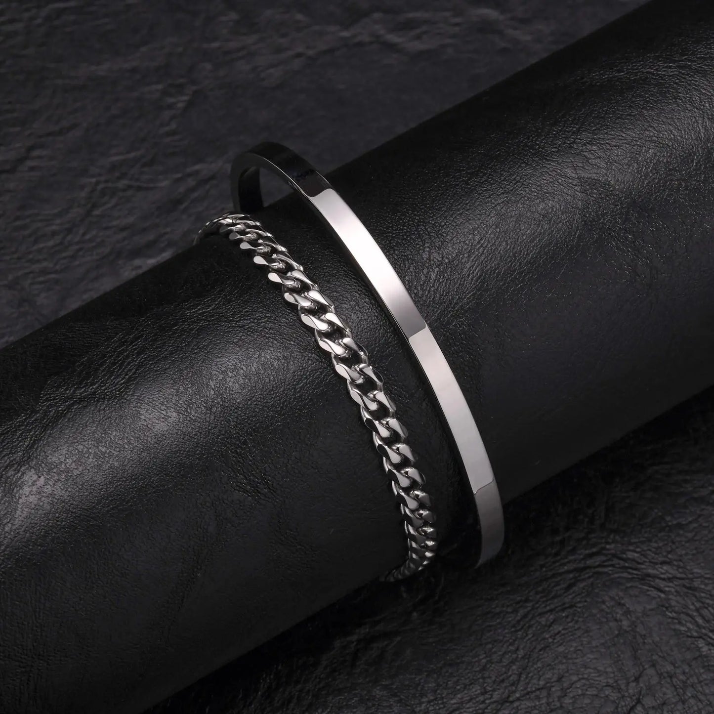 Silver chain bracelet on a black leather surface
