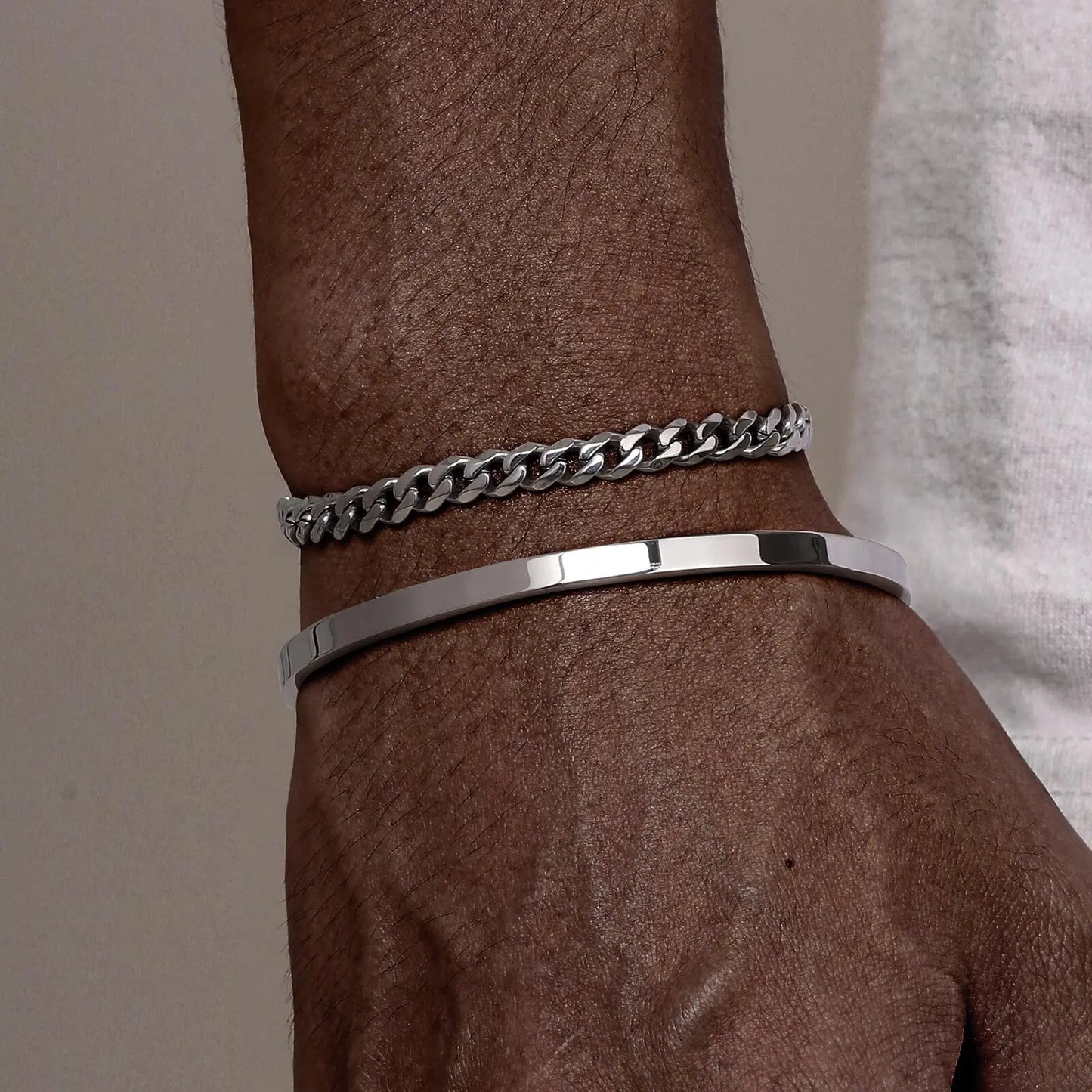 Silver chain bracelet on a wrist with a neutral background