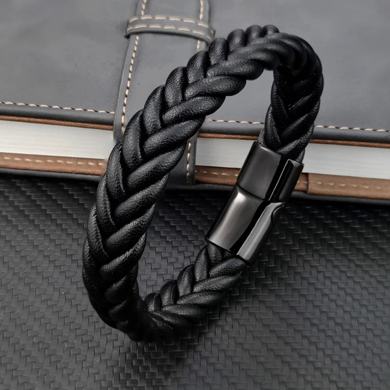 Black braided leather bracelet with a silver clasp on a textured surface