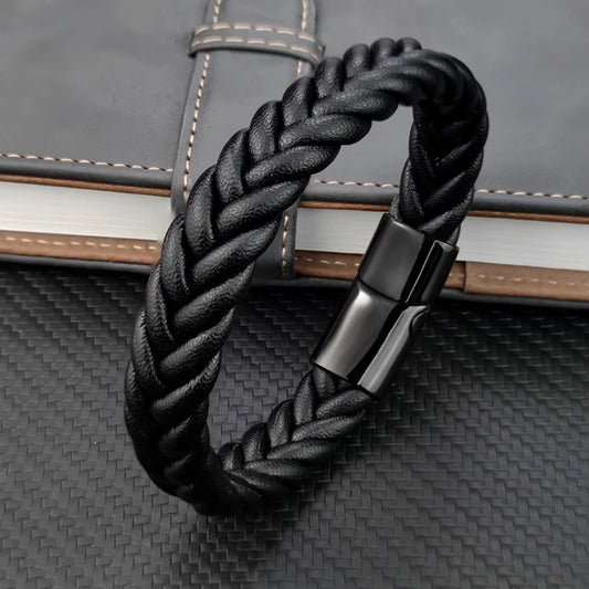 Black braided leather bracelet with a silver clasp on a textured surface