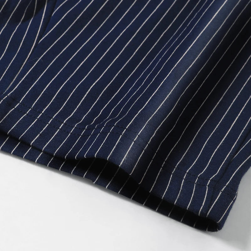 Close-up of navy blue fabric with white pinstripes on a light gray background