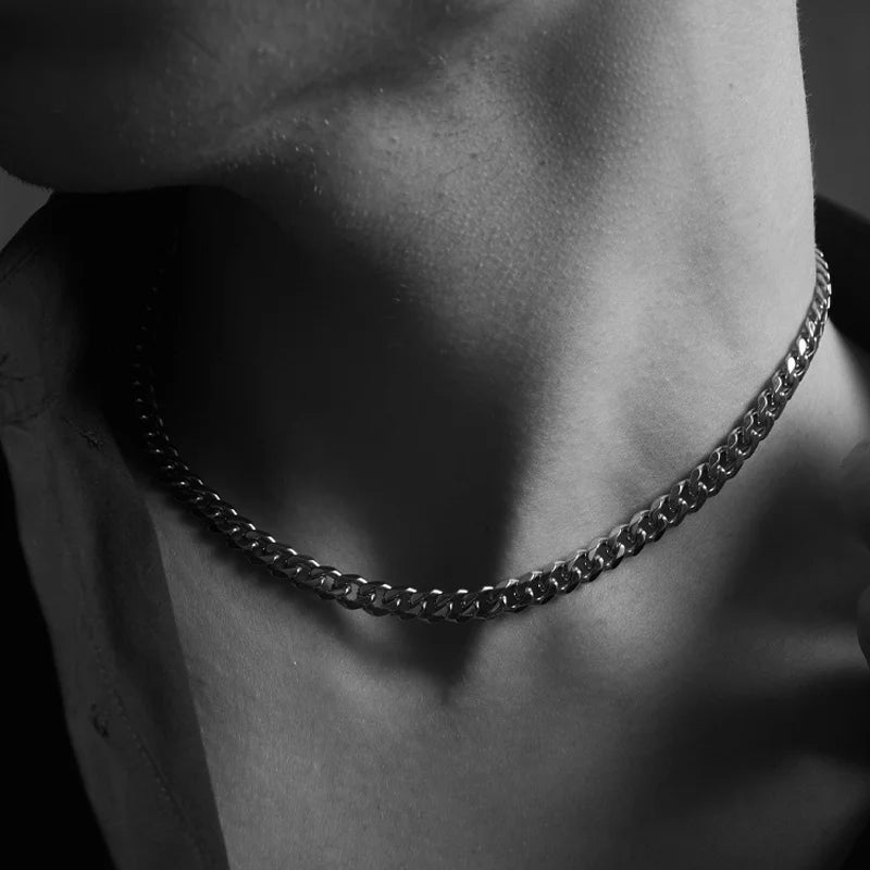 Close-up of a person wearing a chain necklace with a blurred background
